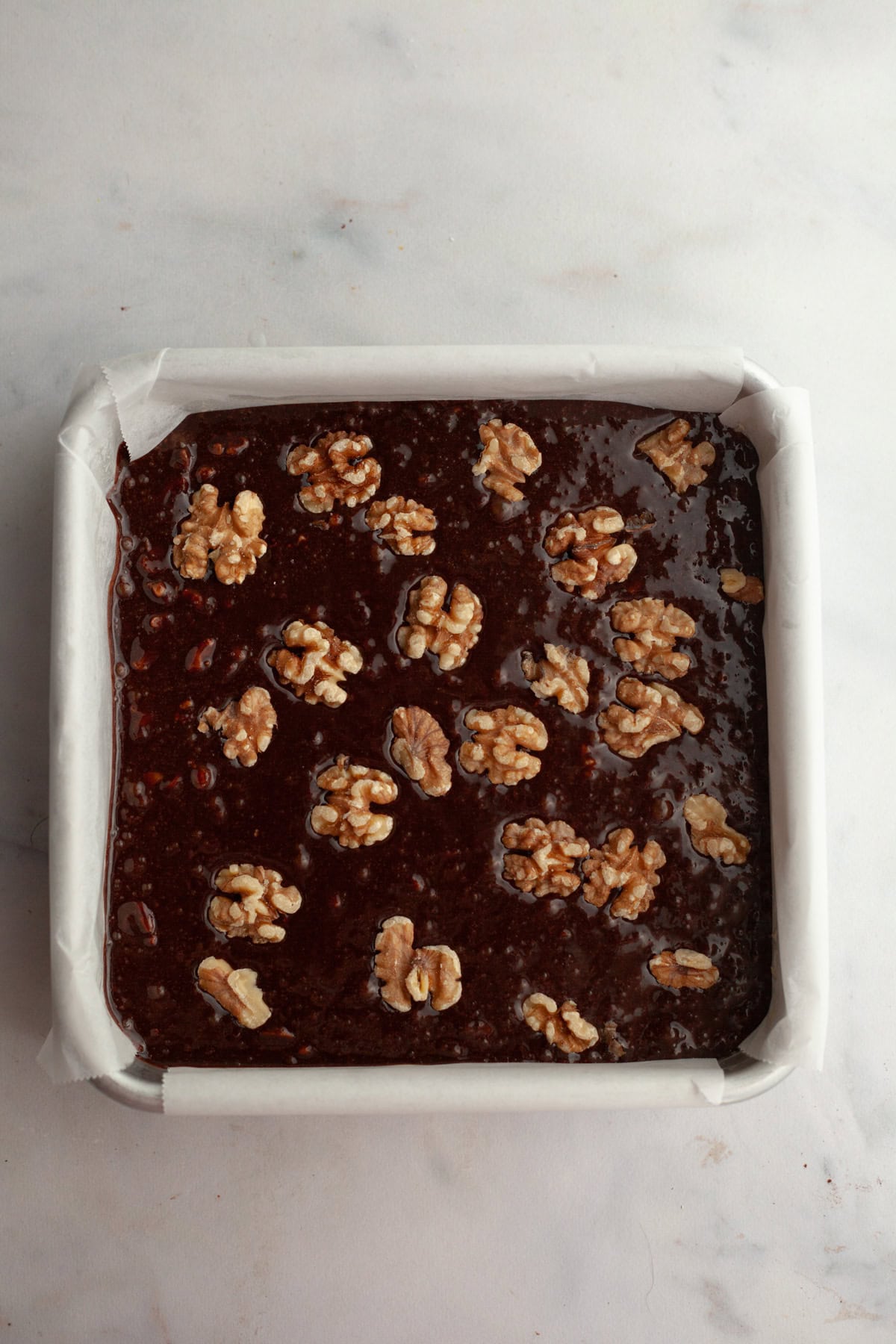 Unbaked walnut brownies in a square pan.