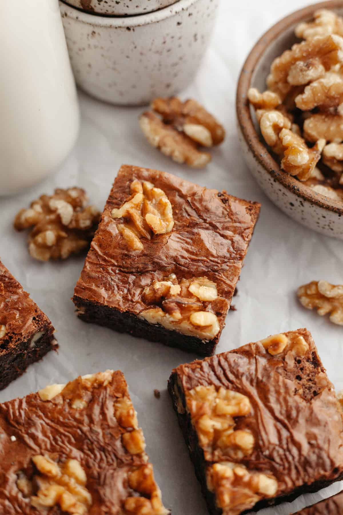 A close up of sliced fudgy walnut brownies on parchment paper.