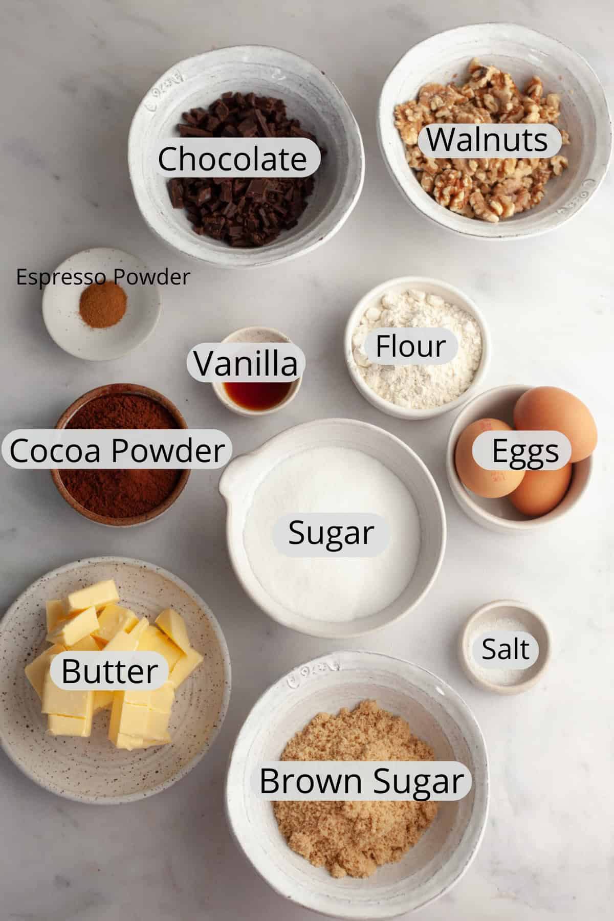 All the ingredients needed to make walnut brownies, weighed out into small bowls.