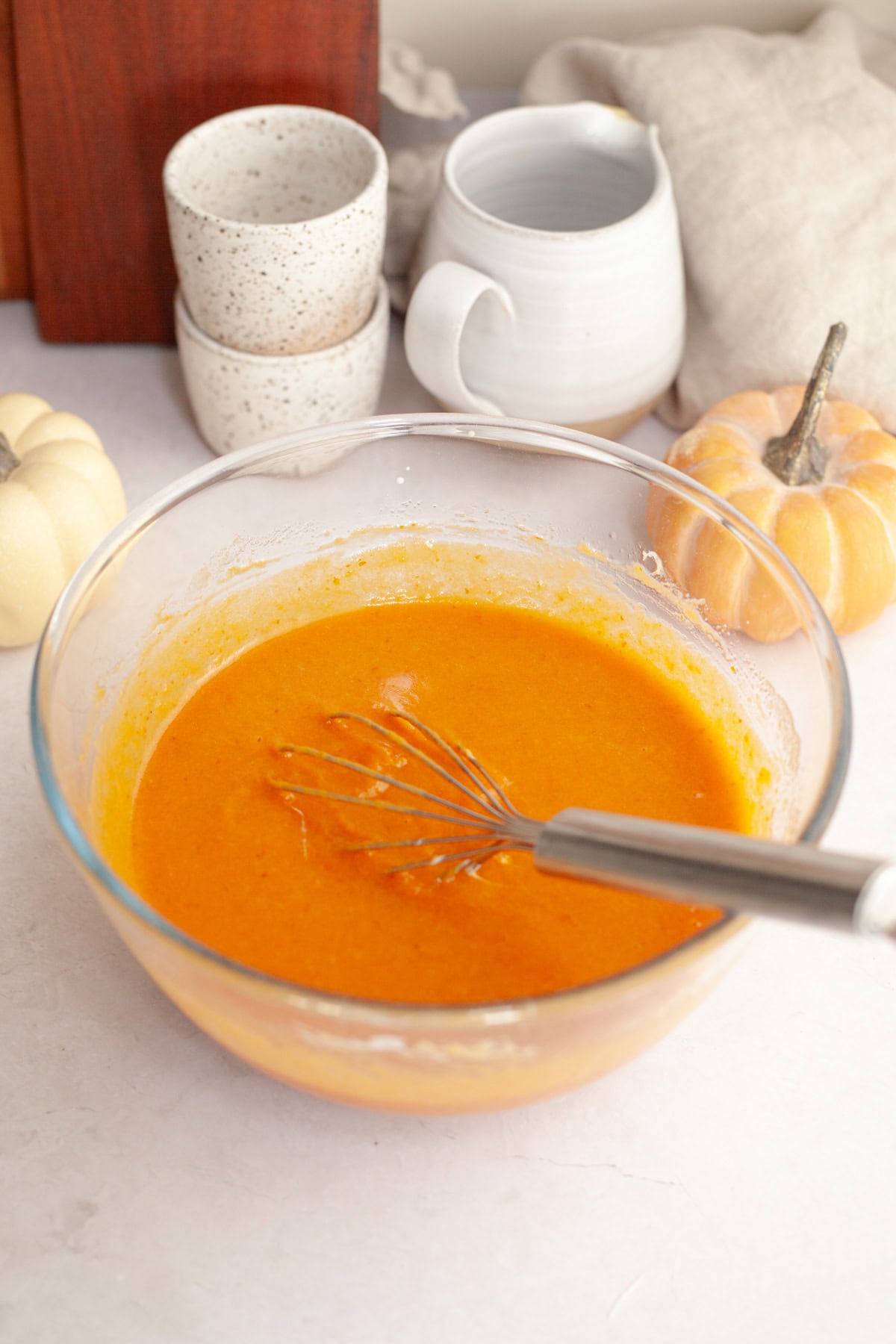 Pumpkin muffin batter in a glass bowl with a whisk.