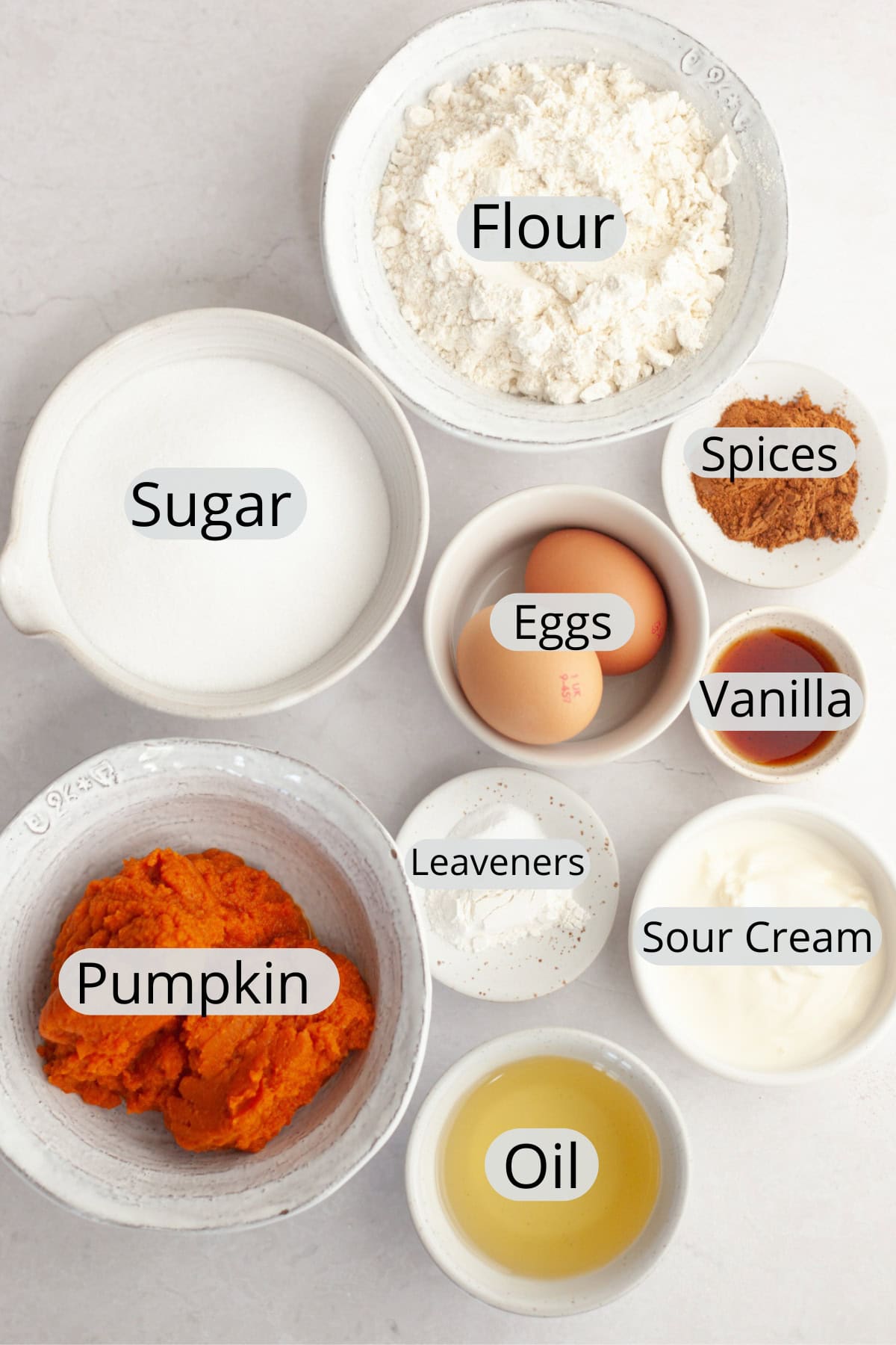 All the ingredients needed to make pumpkin sour cream muffins, weighed out into small bowls.
