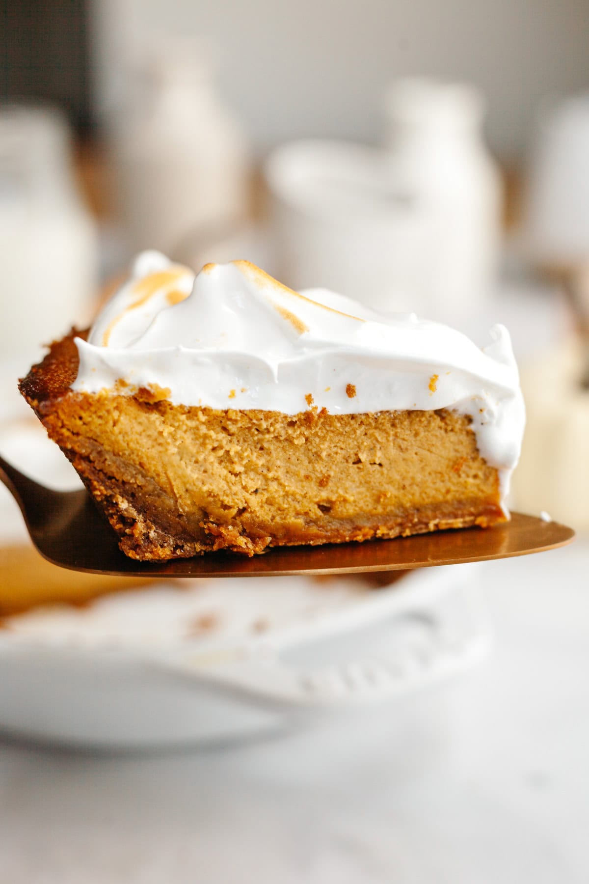 A slice of pumpkin pie with marshmallow topping on a cake server.
