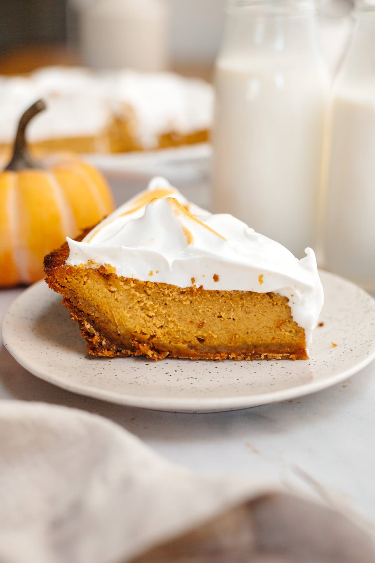 A slice of pumpkin pie with marshmallow topping on a small plate.