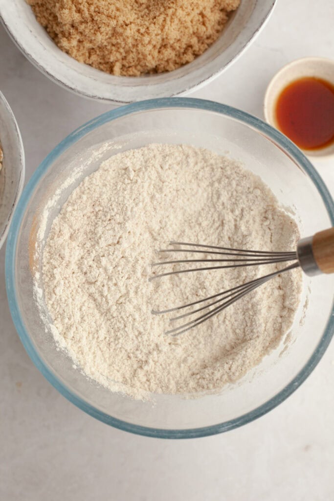 Flour in a small glass bowl with a whisk.
