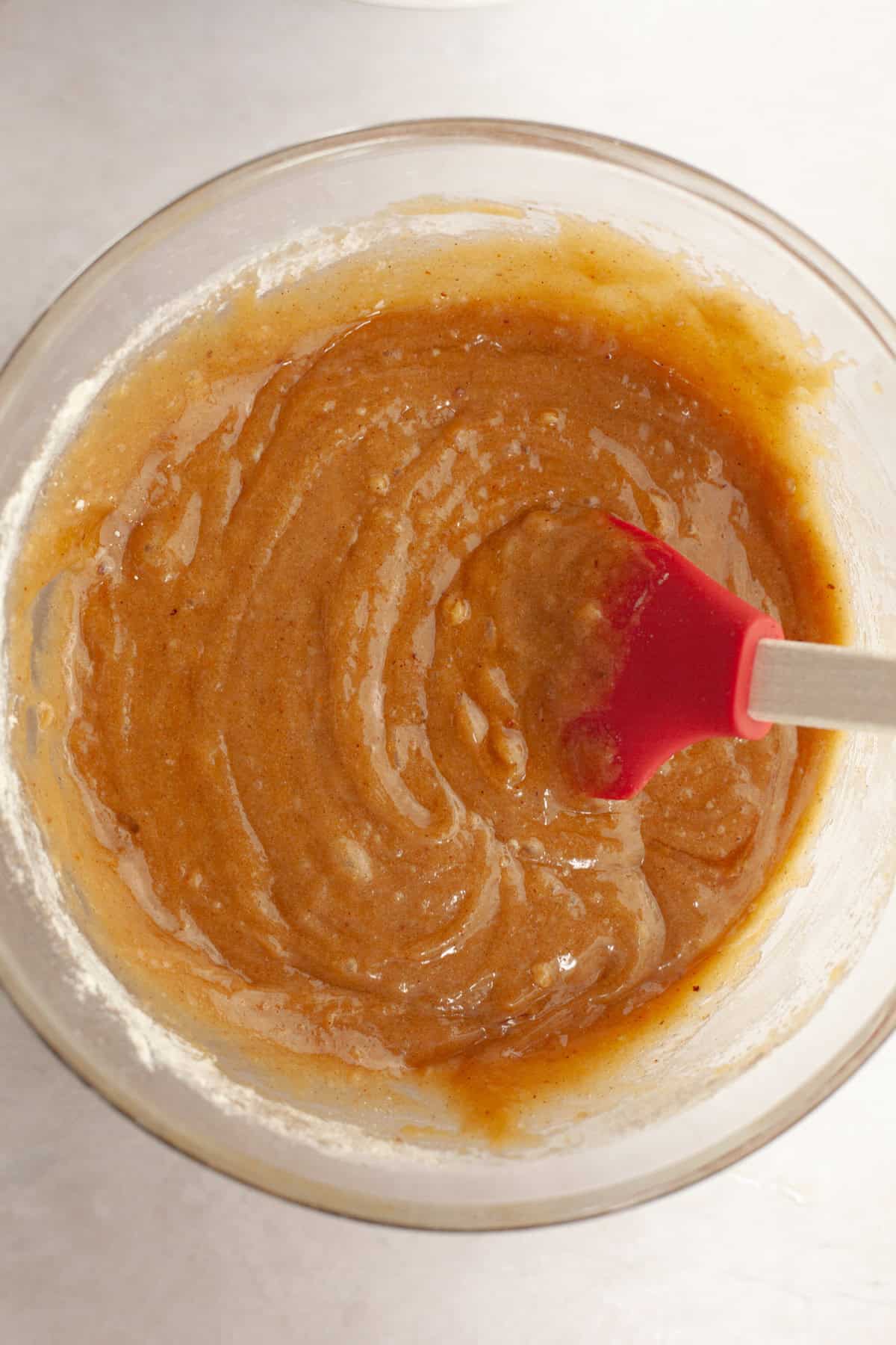 Cookie dough in a glass bowl with a rubber spatula.