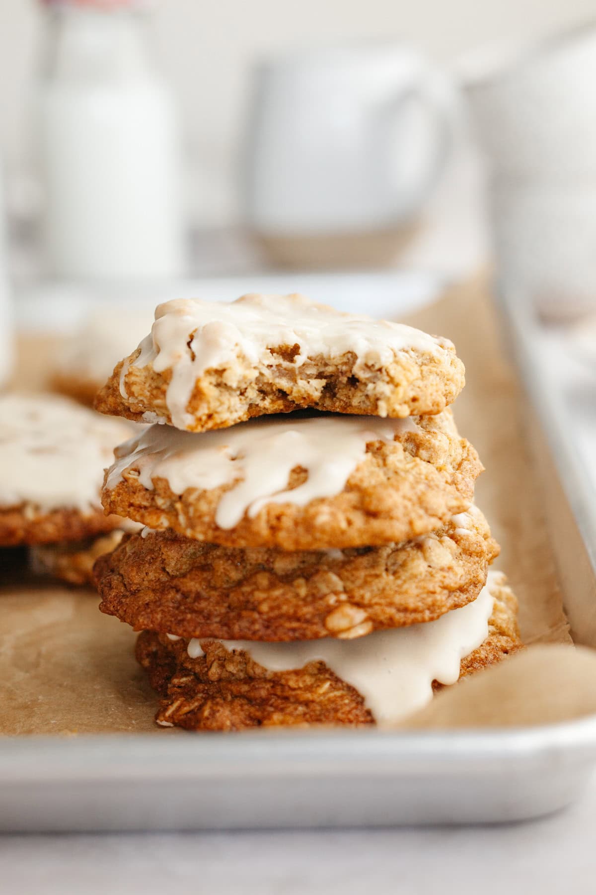 A stack of three glazed oatmeal cardamom cookies, the cookie on top has a bite taken out of it.