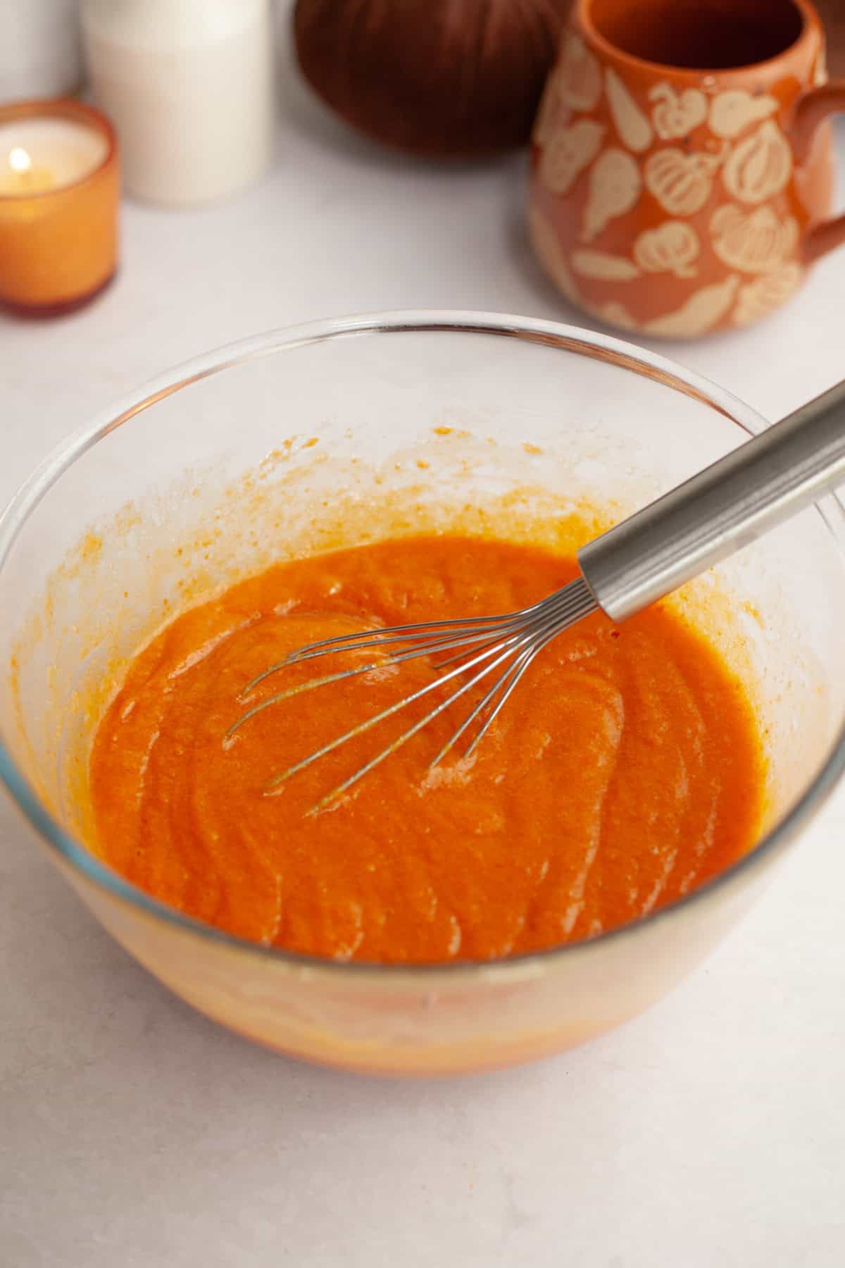 Pumpkin cake batter in a glass bowl with a whisk.