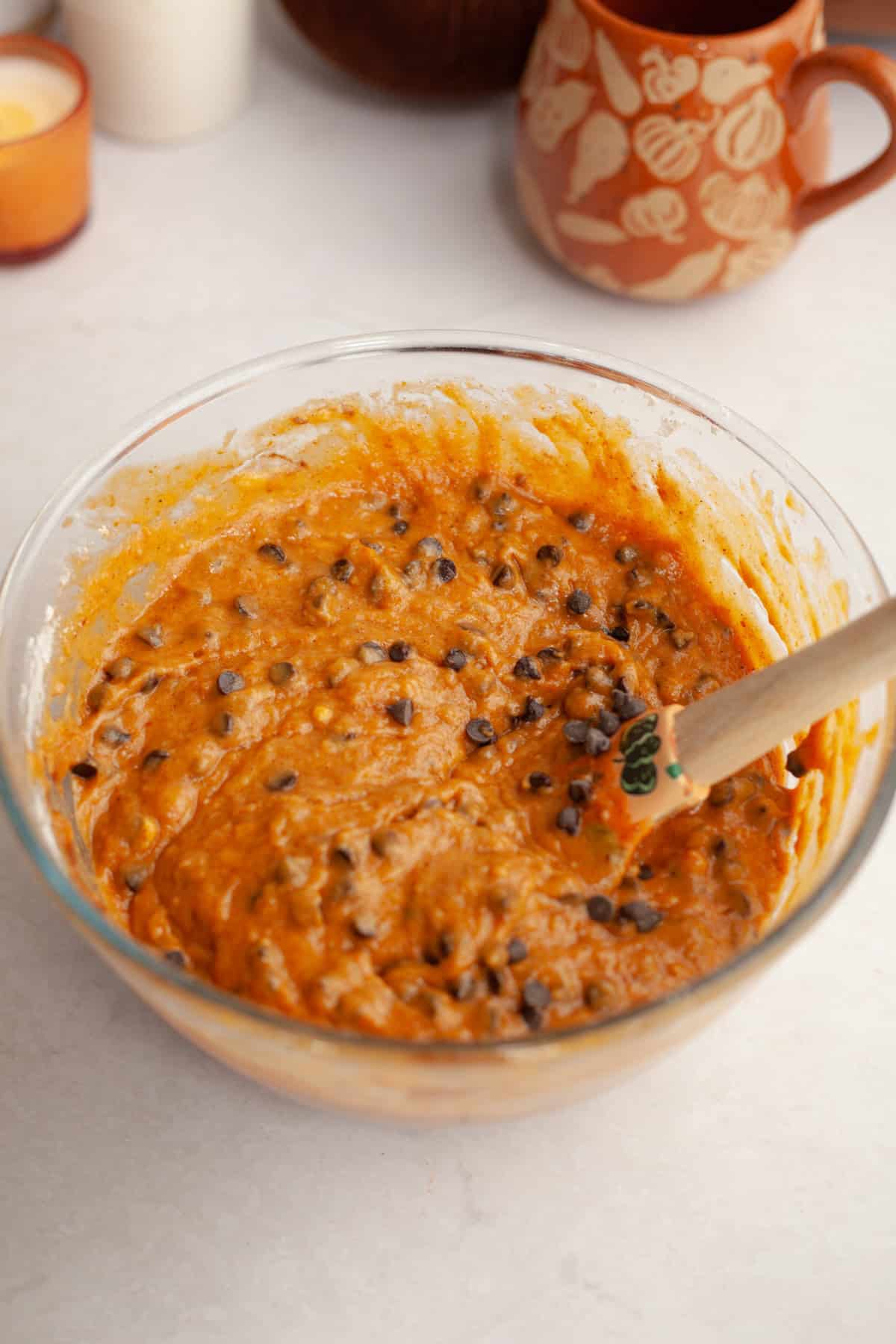 Pumpkin chocolate chip cake batter in a glass bowl with a rubber spatula.
