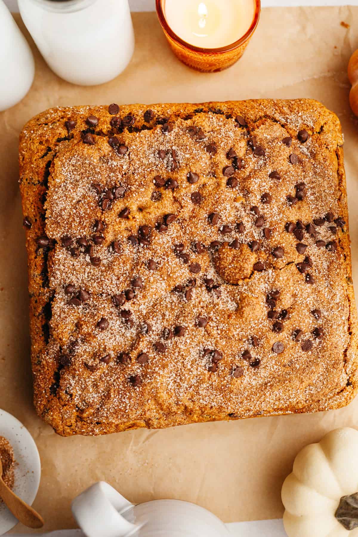 An overhead shot of a square chocolate chip pumpkin cake on parchment paper.