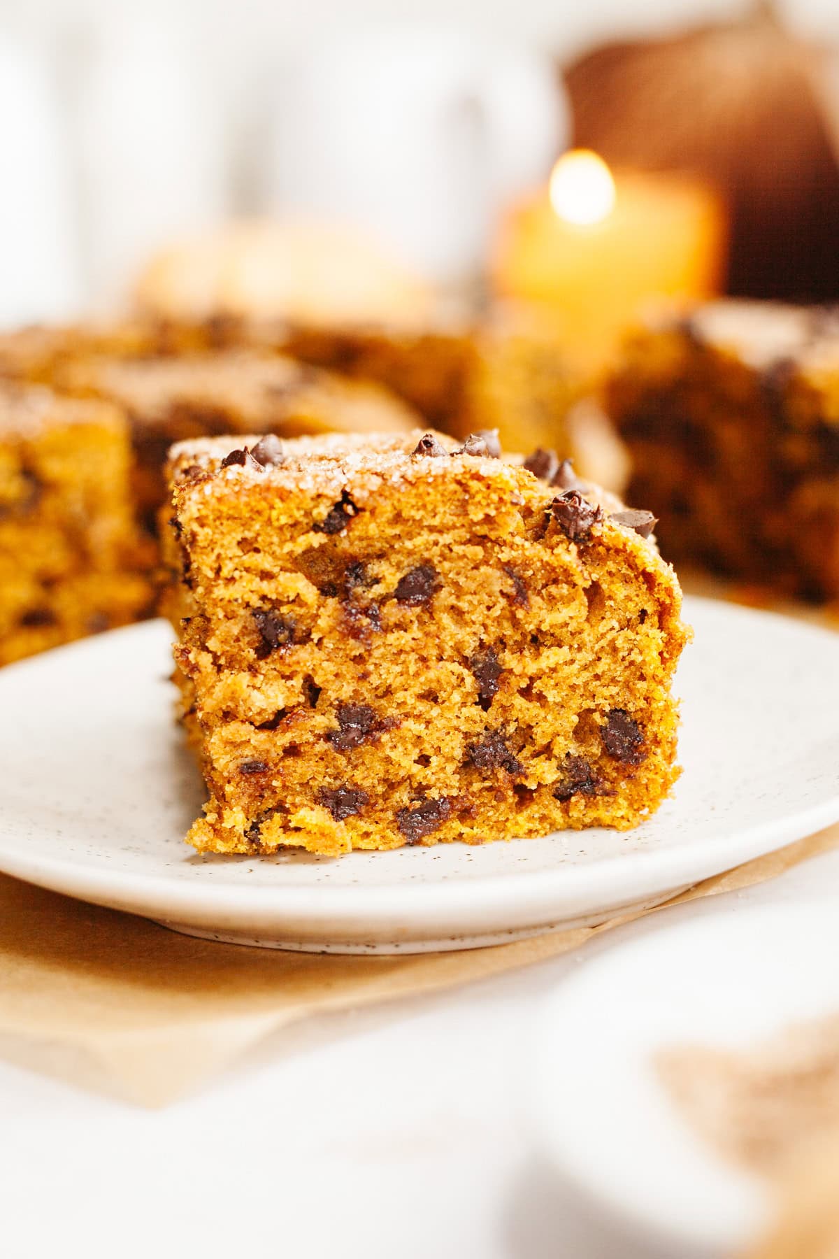A close up of a square slice of pumpkin chocolate chip cake on a small plate.