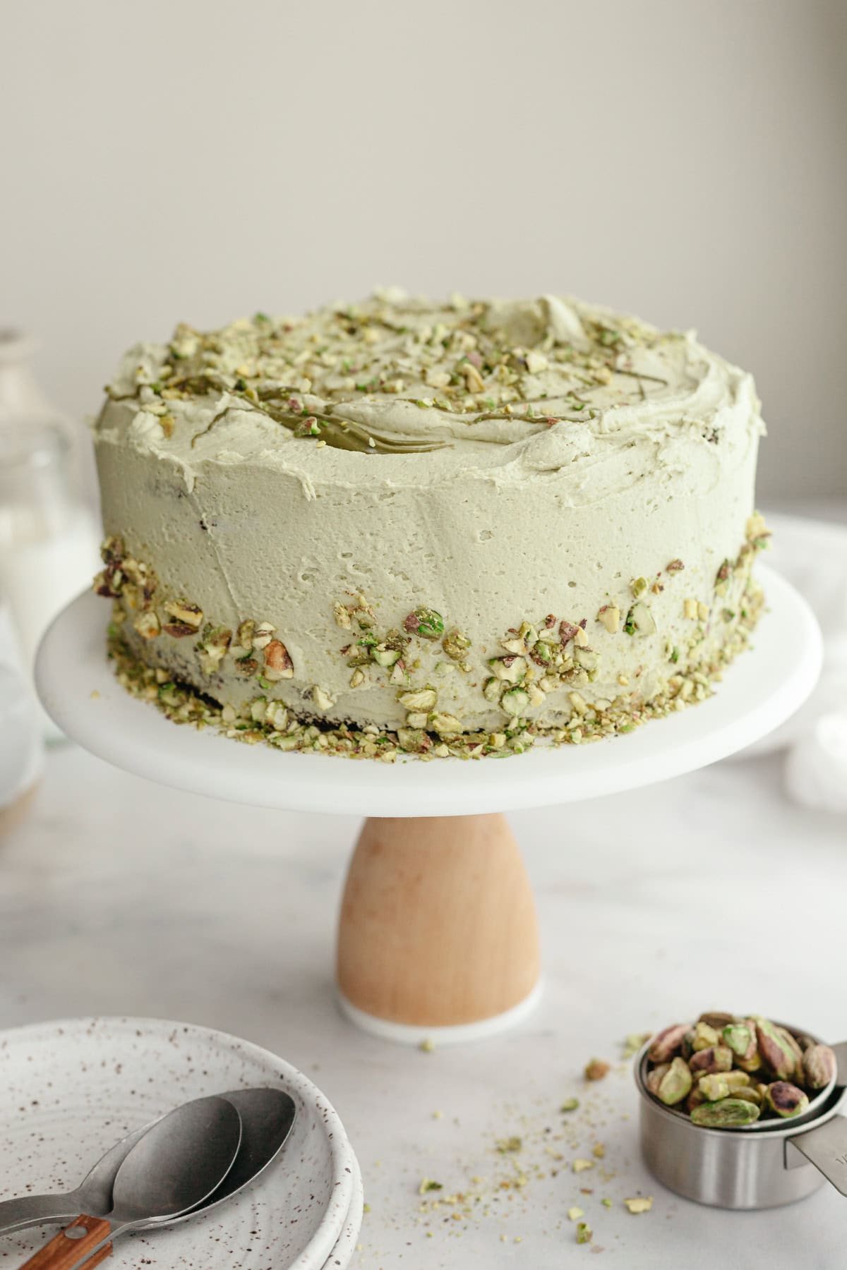 A pistachio frosted cake on a cake stand.