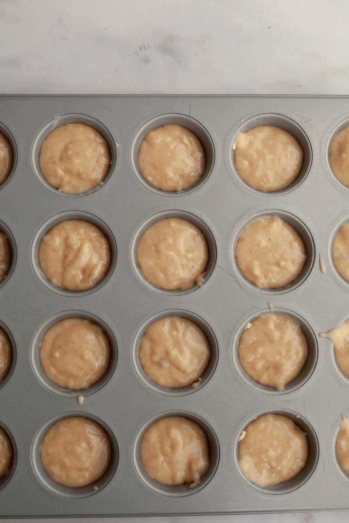 Mini muffin pan filled with unbaked muffin batter.