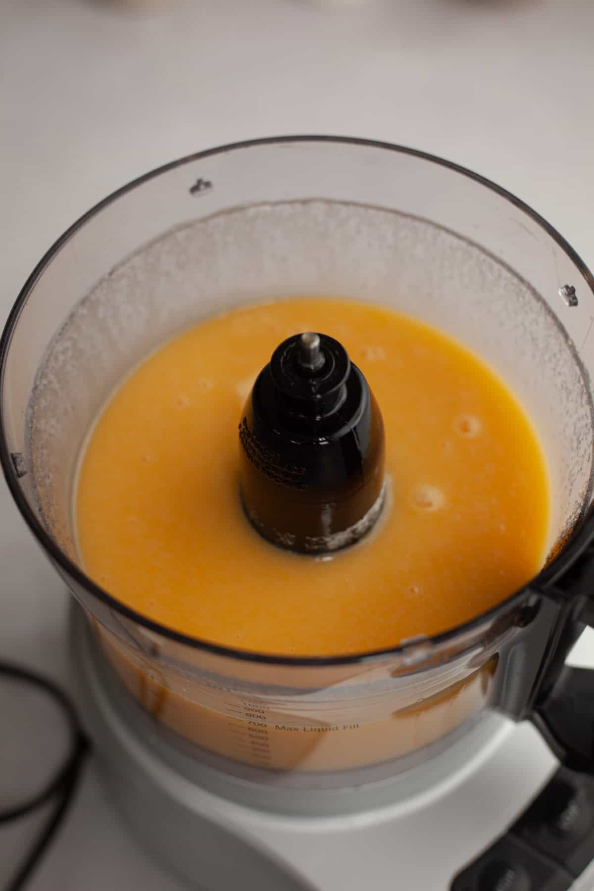 A food processor with a yellow batter in it.