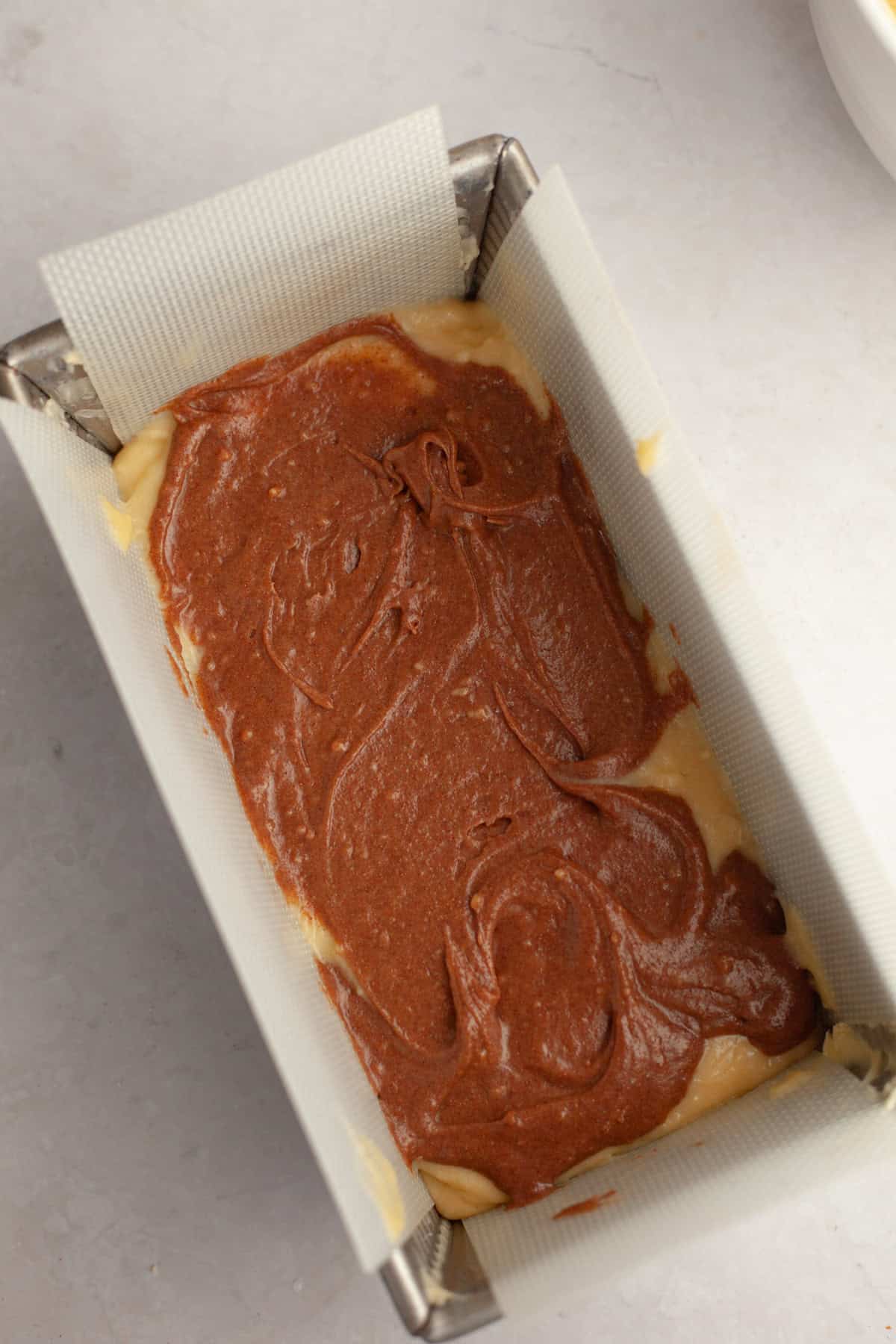 A loaf pan filled with cinnamon cake batter.