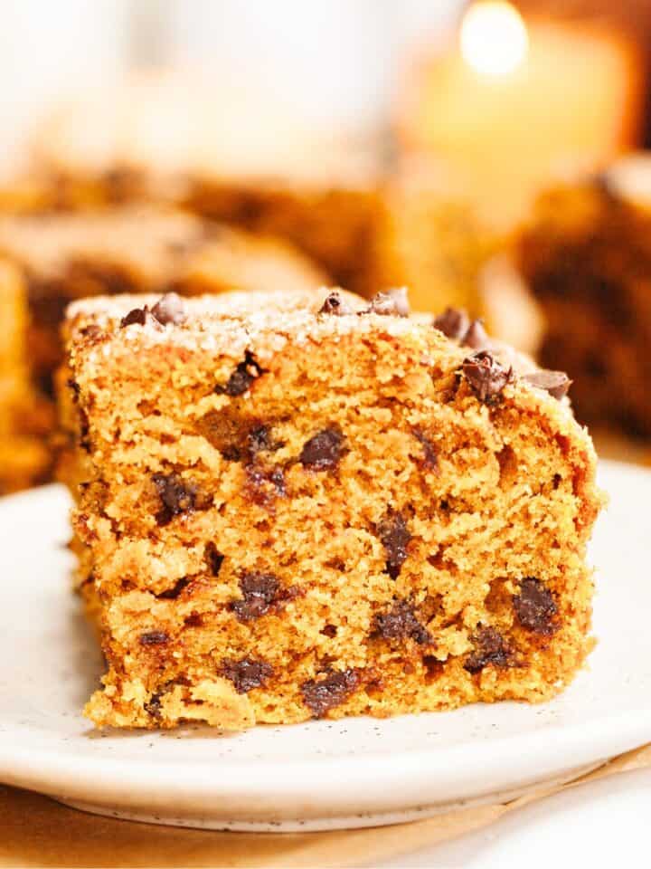 A close up of a square slice of pumpkin chocolate chip cake on a small plate.