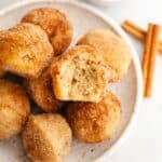 A small plate full of mini cinnamon muffins, one has a bite taken out of it.