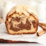 A cinnamon swirl loaf cake sliced on parchment paper.