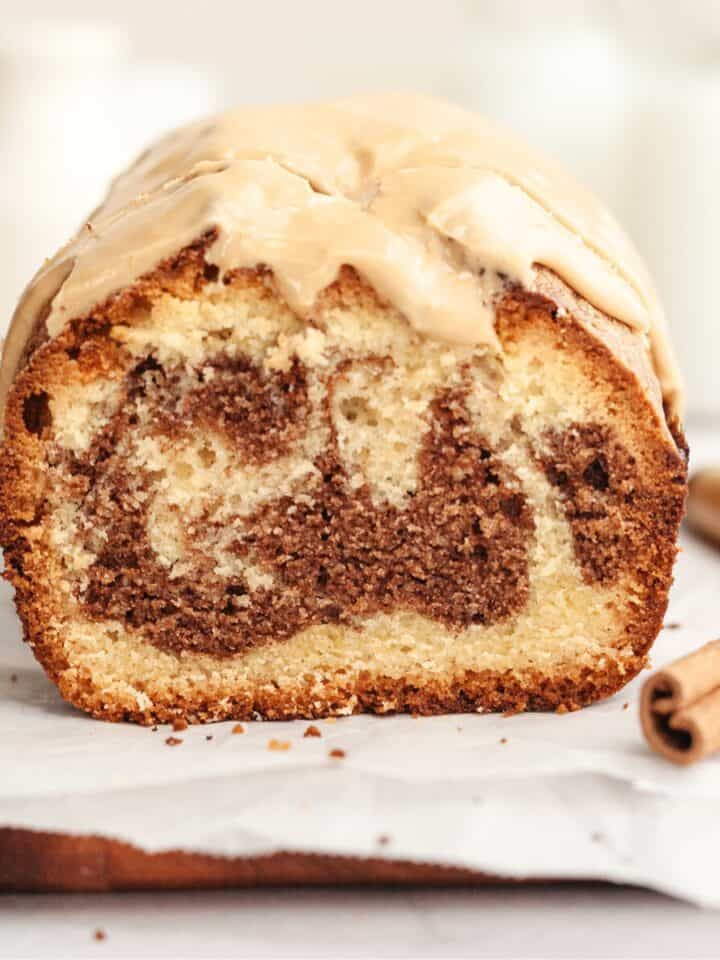 A cinnamon swirl loaf cake sliced on parchment paper.
