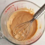 Maple espresso glaze in a glass jug with a whisk.