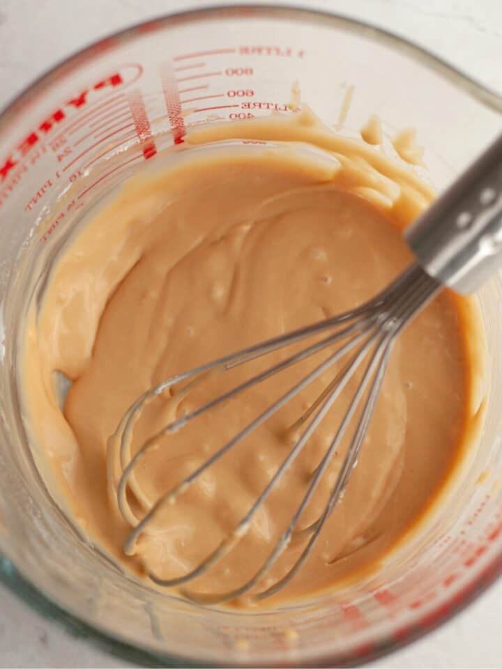 Maple espresso glaze in a glass jug with a whisk.