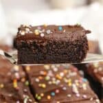 A cake server with a slice of chocolate sheet cake with chocolate frosting.