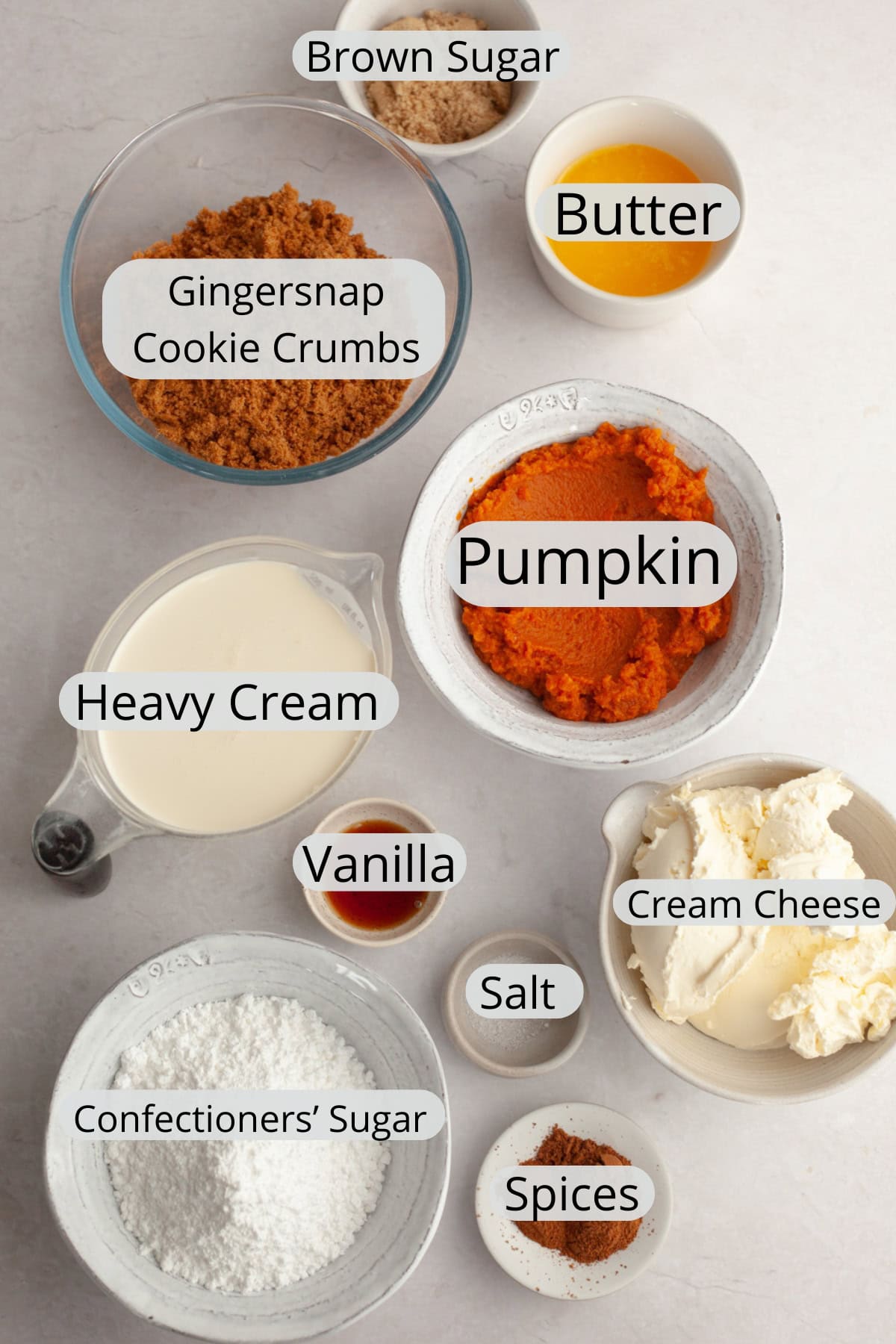 All the ingredients needed to make pumpkin cheesecake bars, weighed out into small bowls.