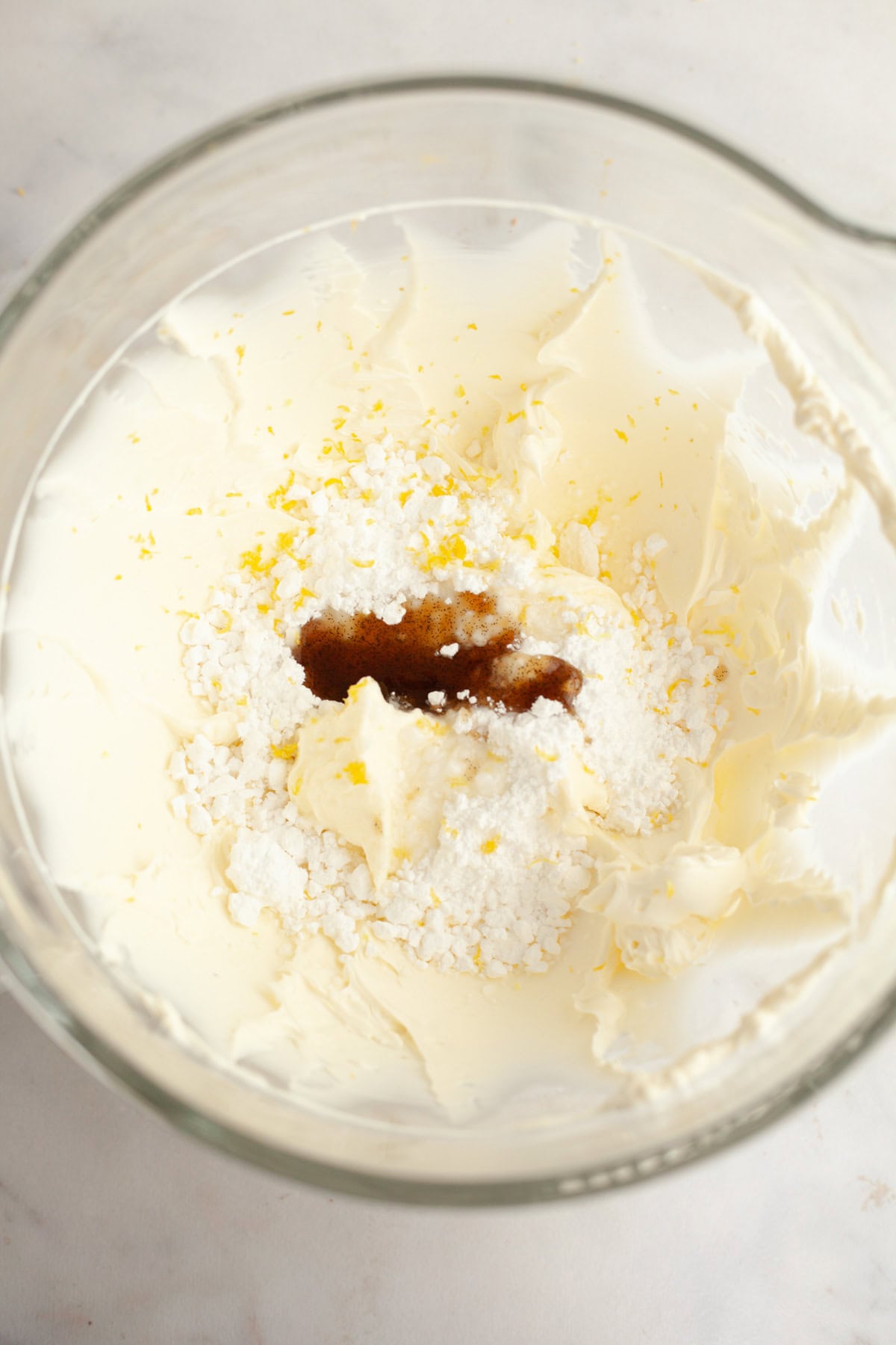 A large mixing bowl with cream cheese, lemon zest, sugar, and vanilla.