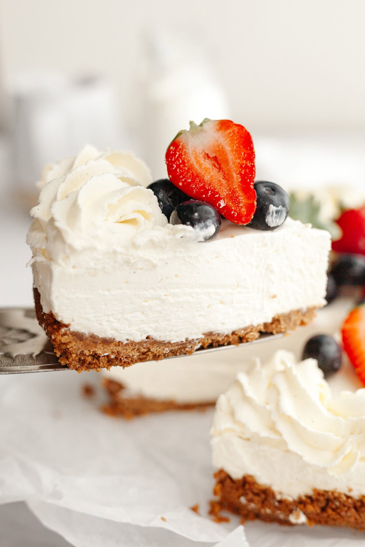 A close up of a vanilla no bake cheesecake, decorated with fresh berries.