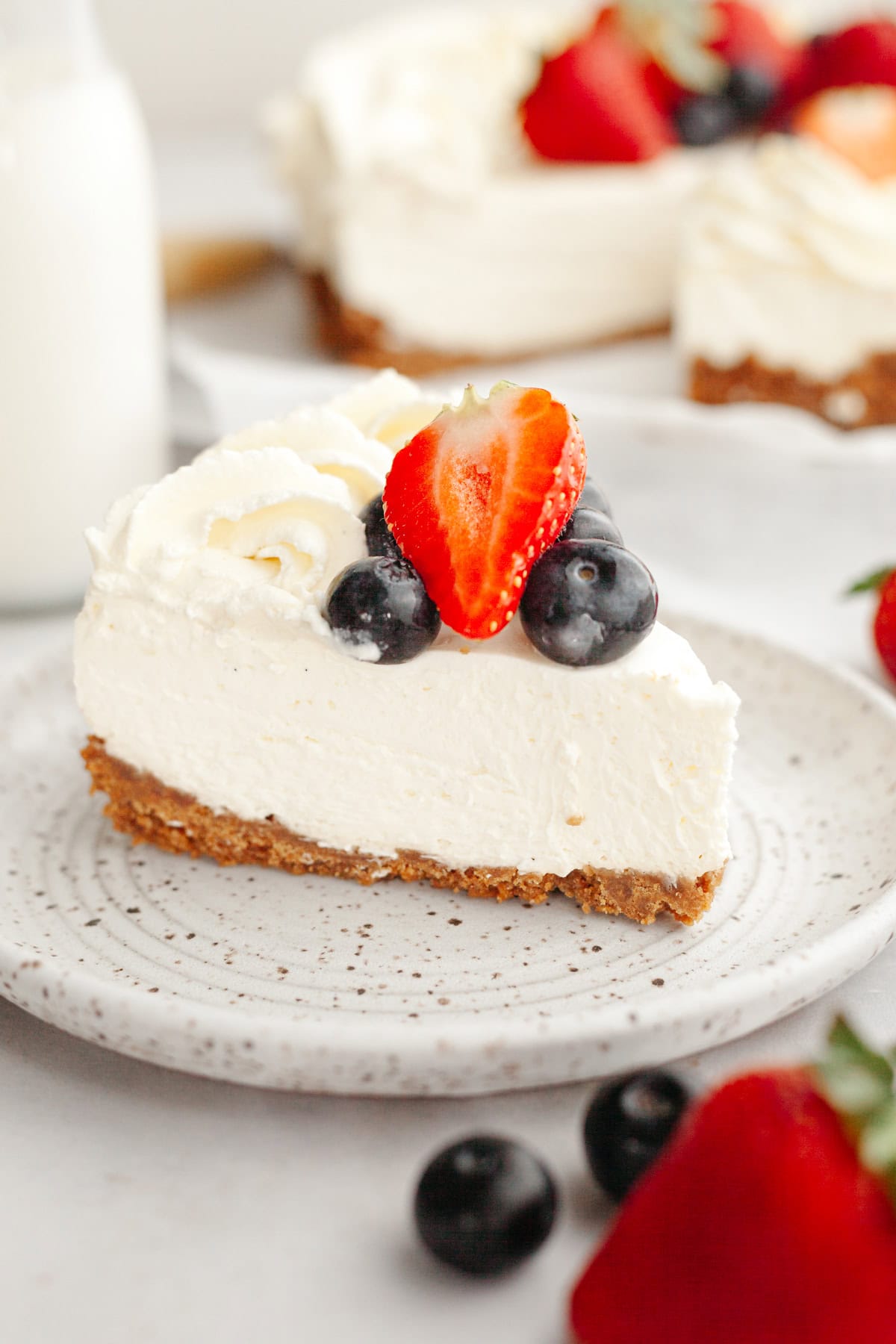 A close up of a vanilla no bake cheesecake, decorated with fresh berries.