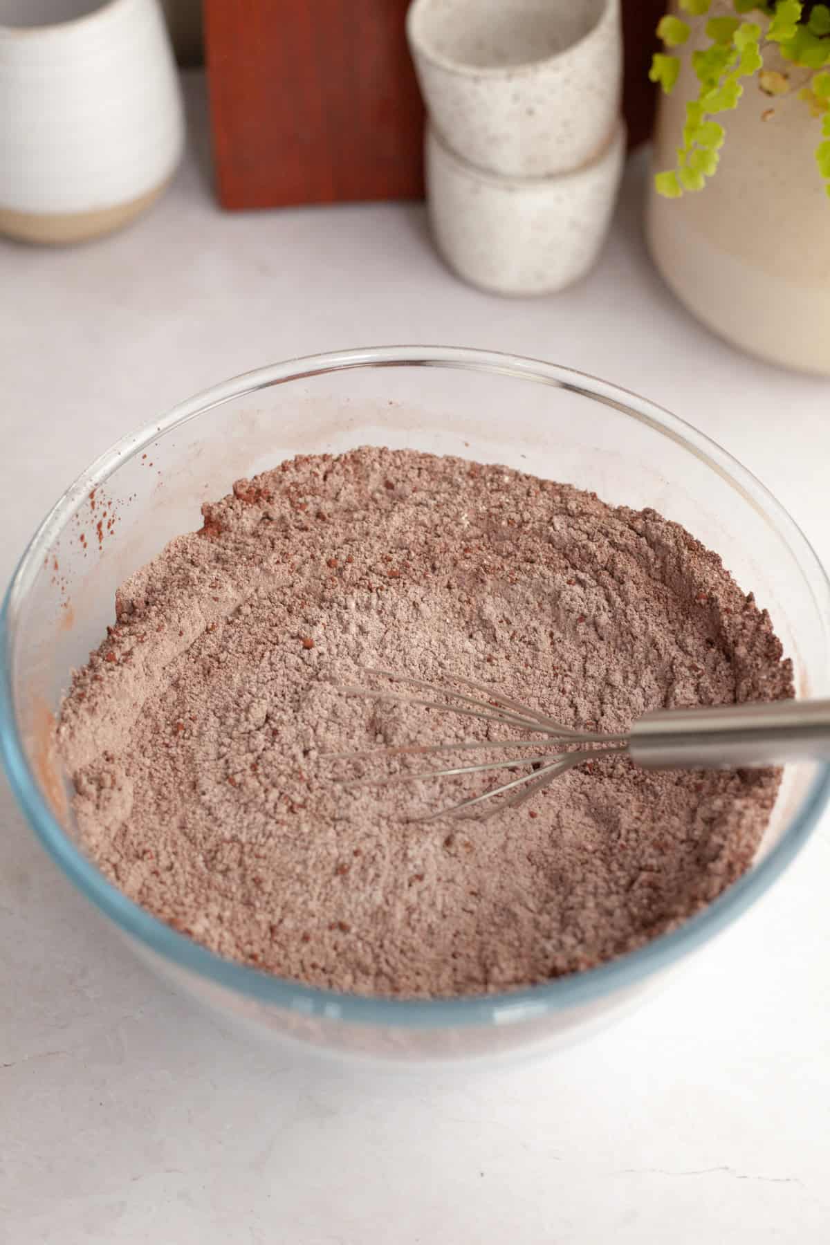 Flour and cocoa powder in a glass bowl with a whisk.