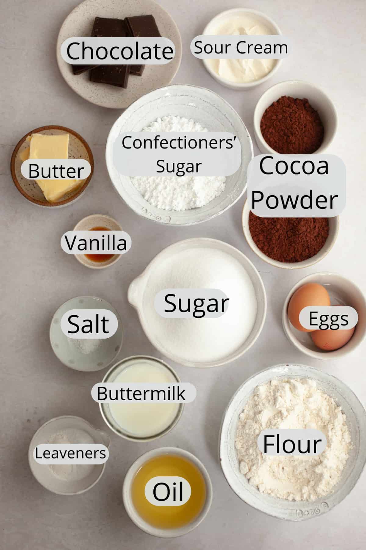 All the ingredients needed to make a single layer chocolate cake with chocolate sour cream frosting, weighed out into small bowls.
