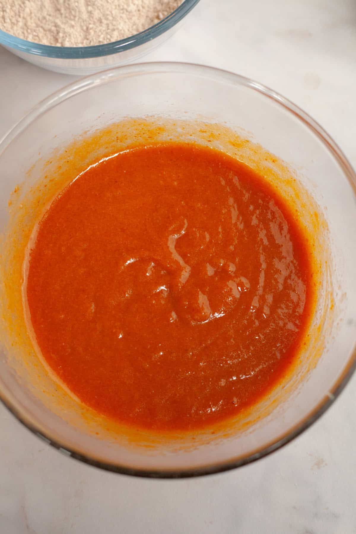 Pumpkin cupcake batter in a glass bowl.