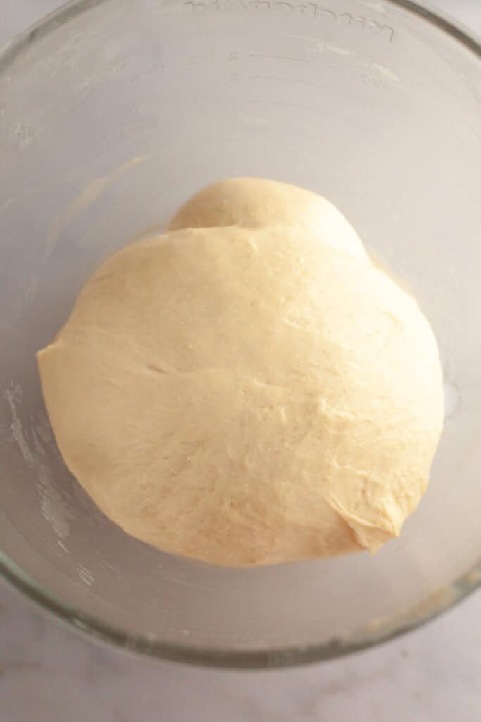 Cinnamon roll dough in a glass bowl.