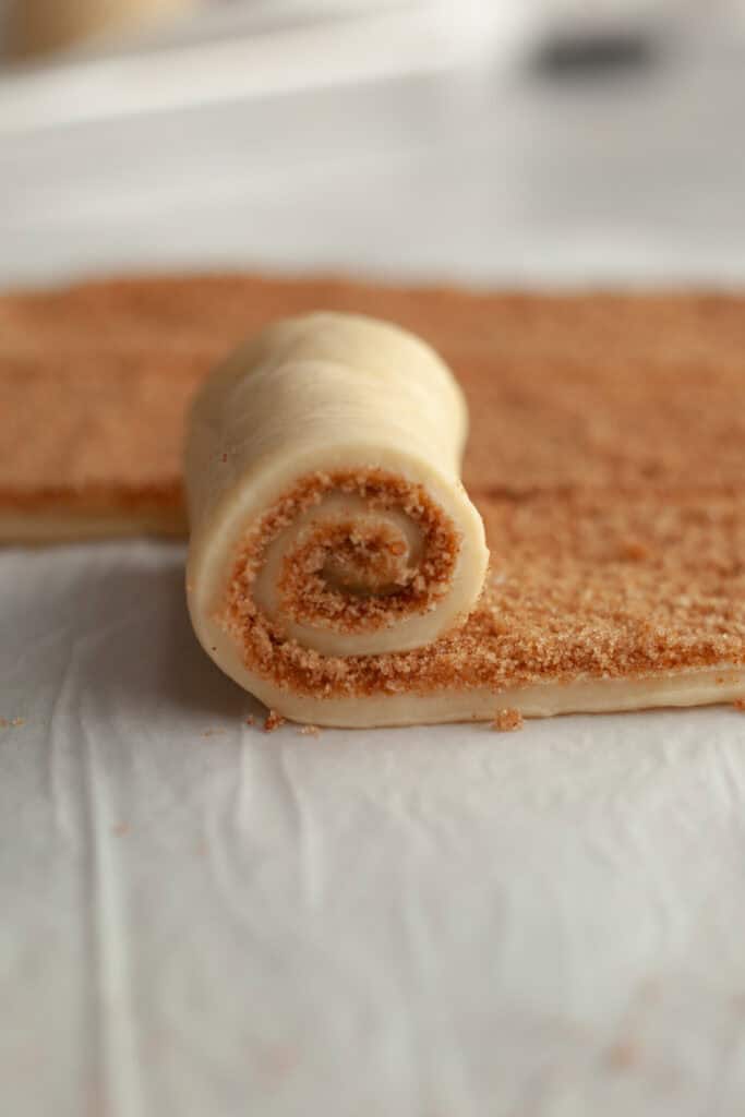 A cinnamon roll being rolled up.