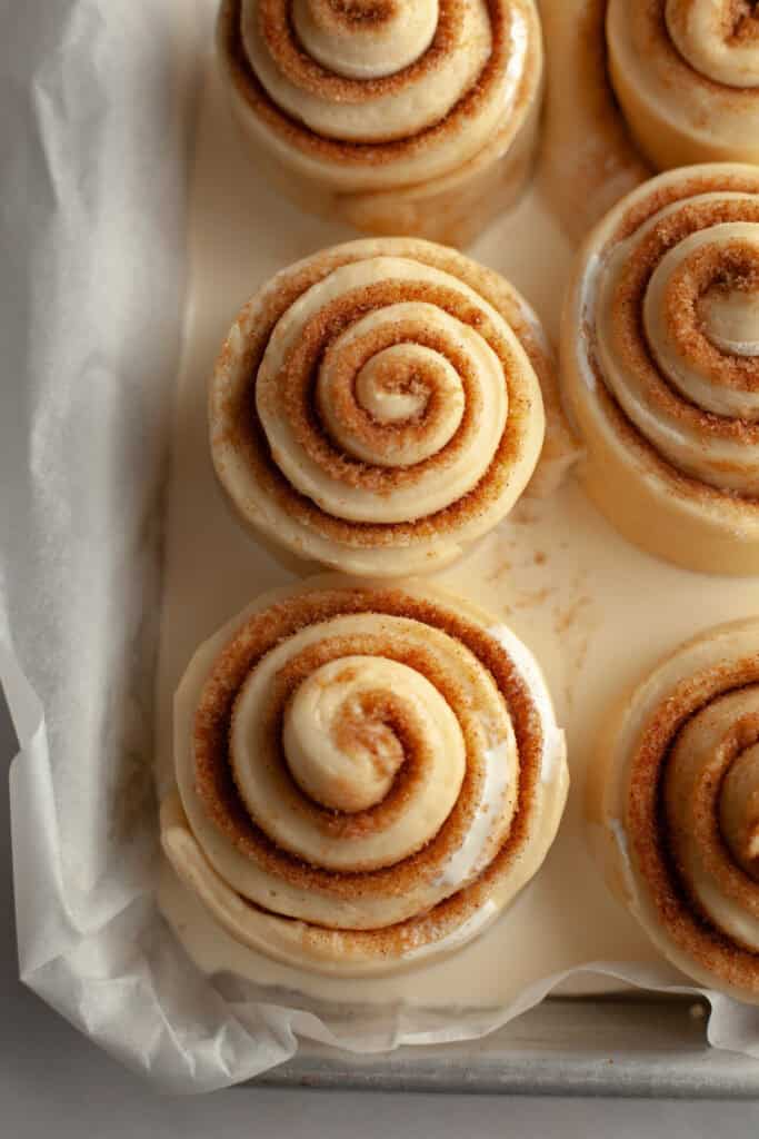 Unbaked cinnamon rolls in a small pan with heavy cream.
