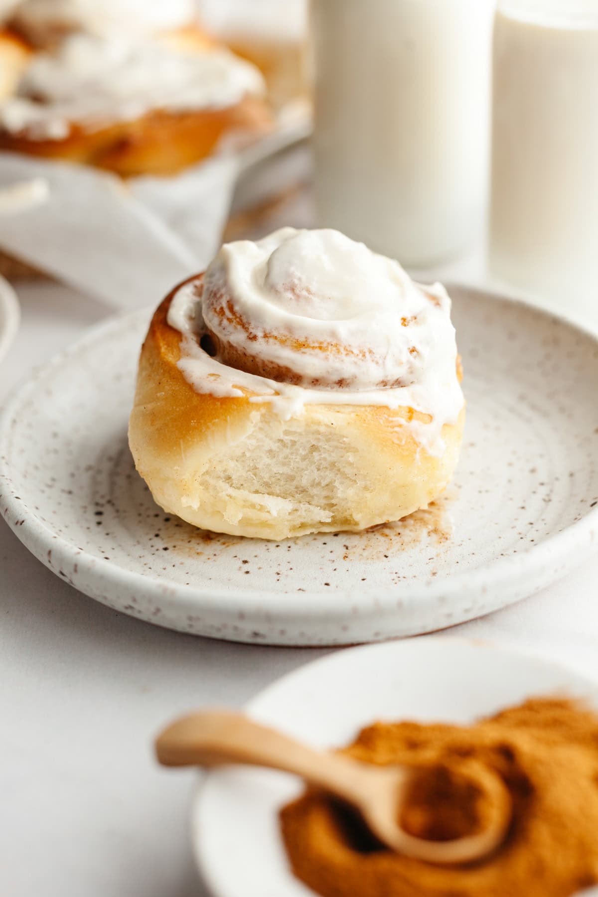 A cinnamon roll with cream cheese icing on a small plate.