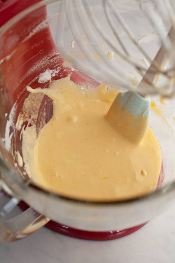 A glass stand mixer bowl with a pale yellow batter.