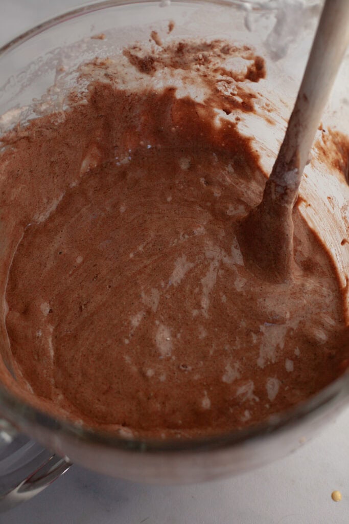 A glass mixing bowl with chocolate cake batter.