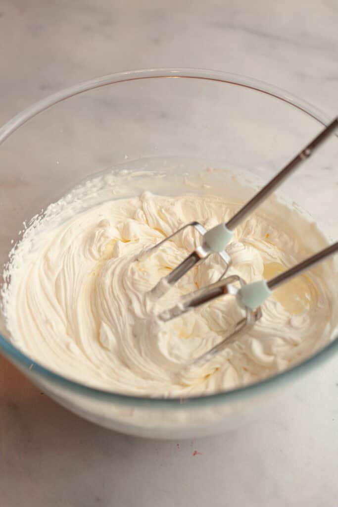 A glass bowl with whipped cream in it.
