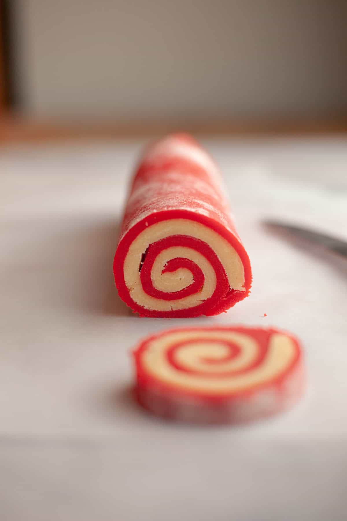 A log of cookie dough in a spiral pattern with red and white dough.