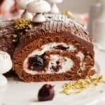 A black forest yule log sliced on a white platter.