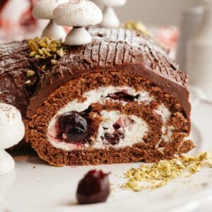 A black forest yule log sliced on a white platter.