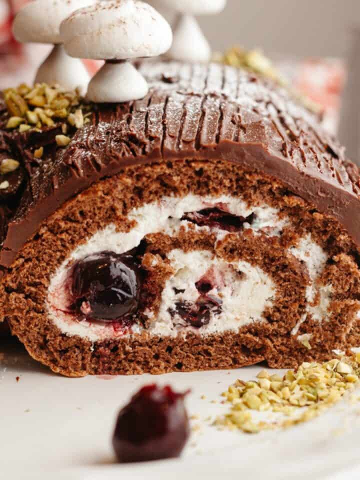A black forest yule log sliced on a white platter.