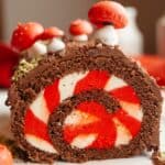 A peppermint bark yule log that has been sliced, showing a white and red striped filling.