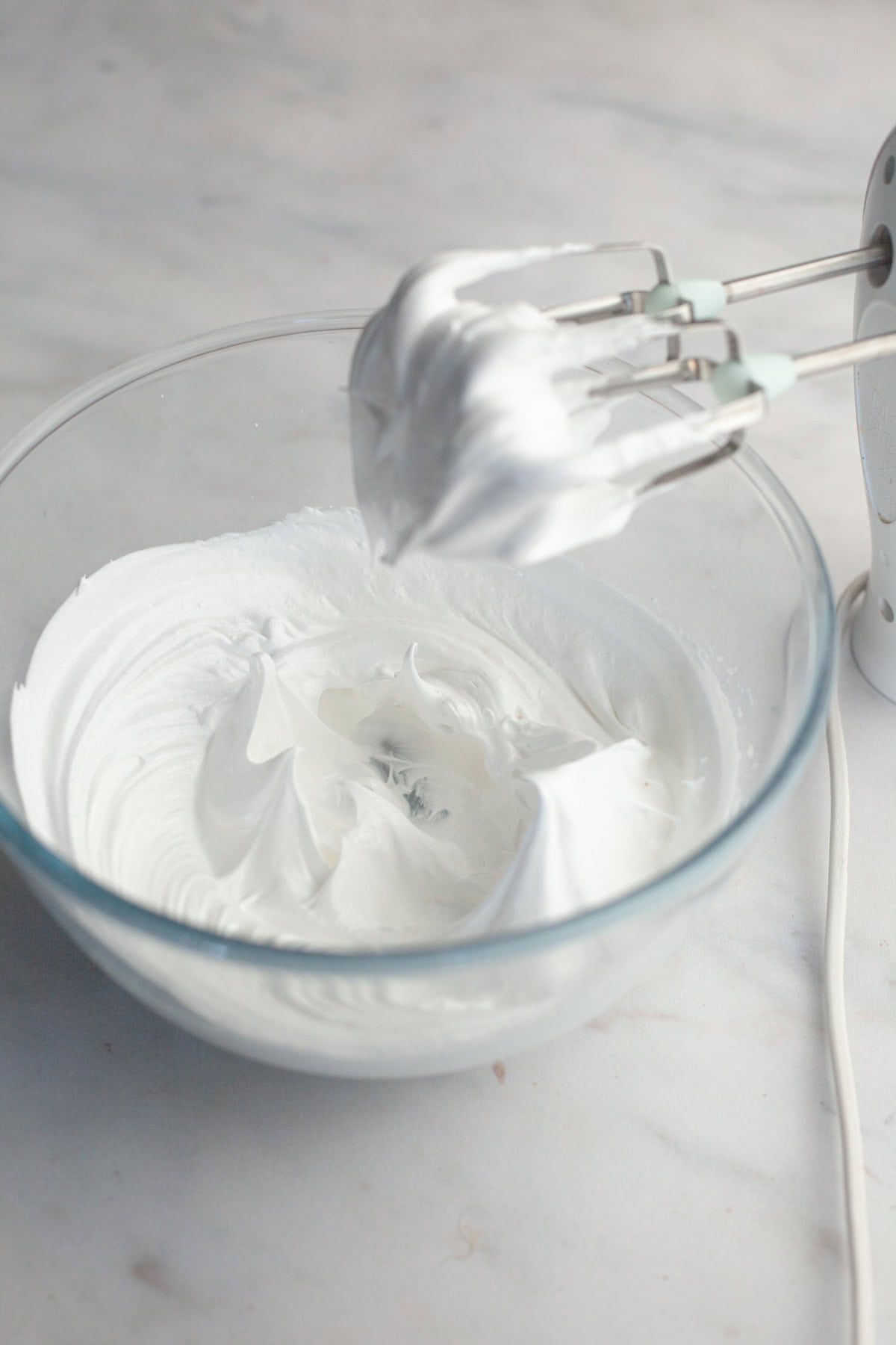 A glass bowl with stiff glossy meringue peaks.
