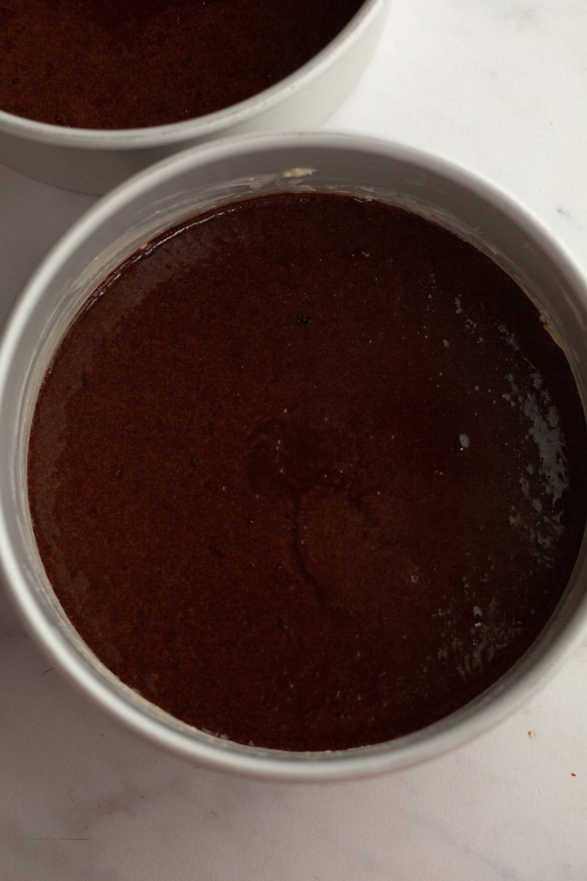A cake pan with unbaked chocolate cake batter.