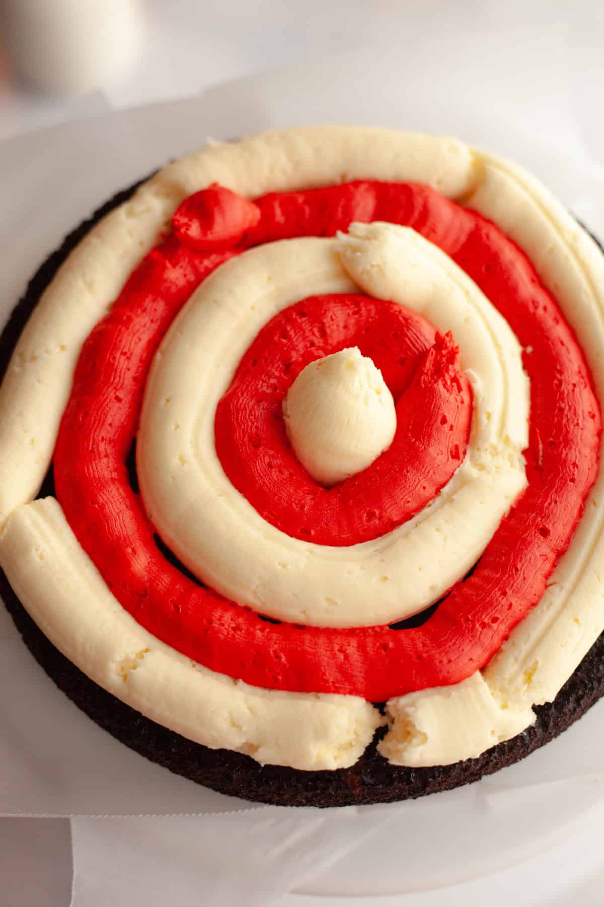 A chocolate cake with white and red frosting, piped into a bullseye.