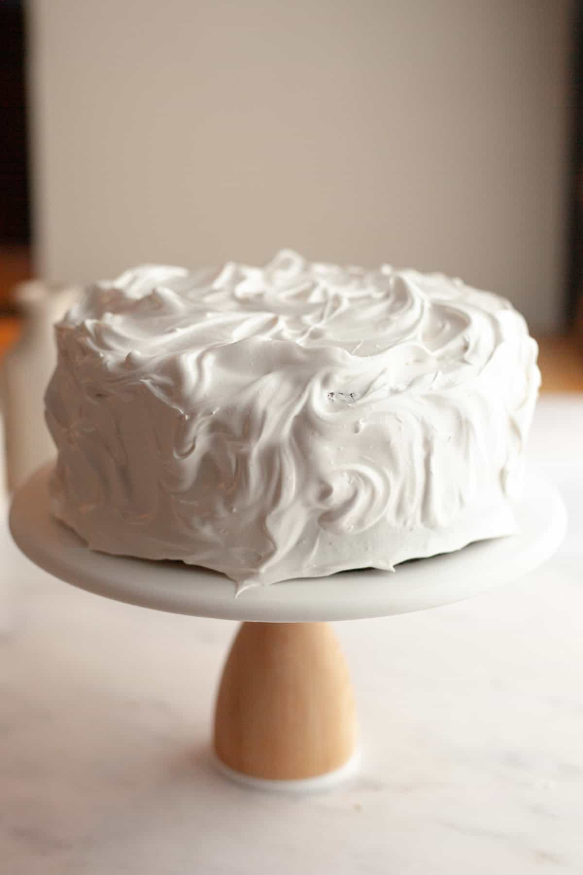 A marshmallow meringue frosted cake on a cake stand.