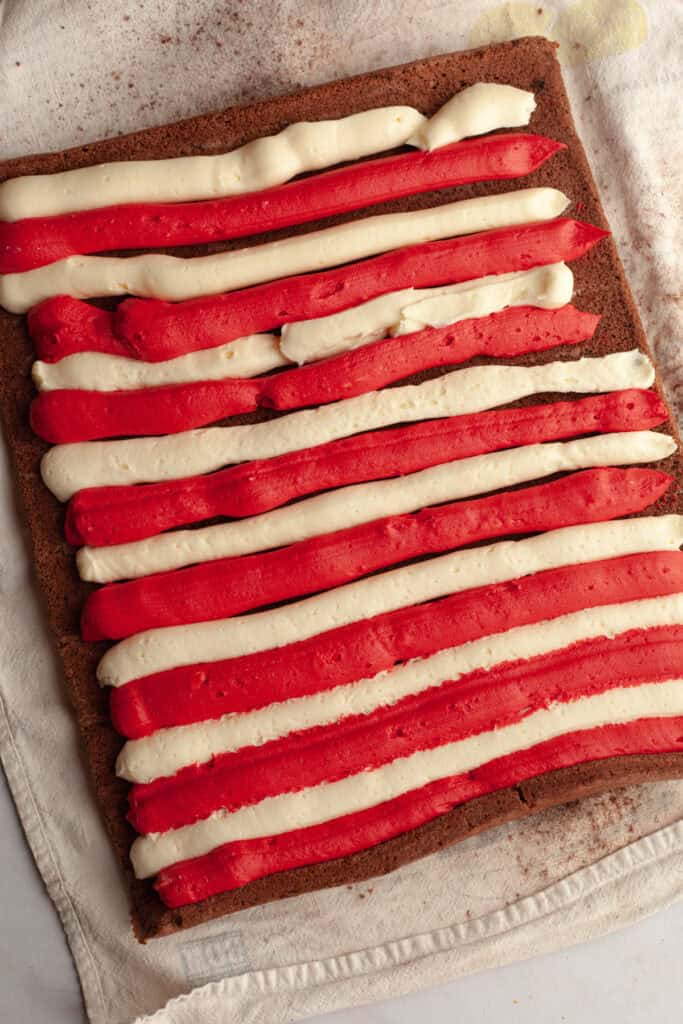 A large rectangular chocolate cake with red and white frosting piped into stripes on top.