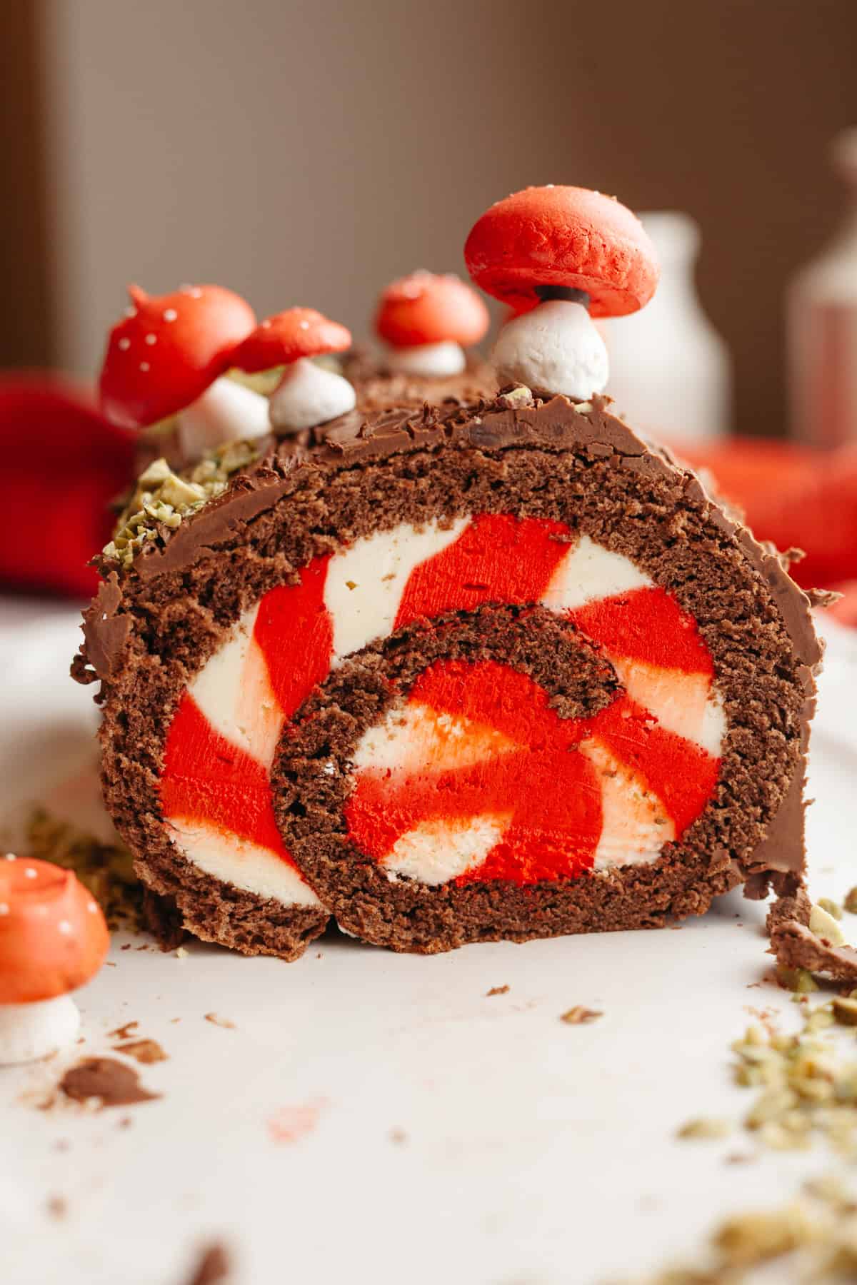 A chocolate yule log with white and red striped filling, decorated with meringue mushrooms on a white platter.